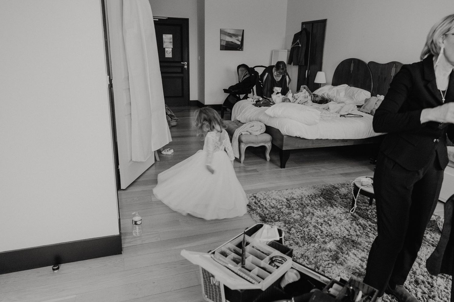 Black and white panoramic photo showing a messy hotel room interior with scattered belongings and furniture.