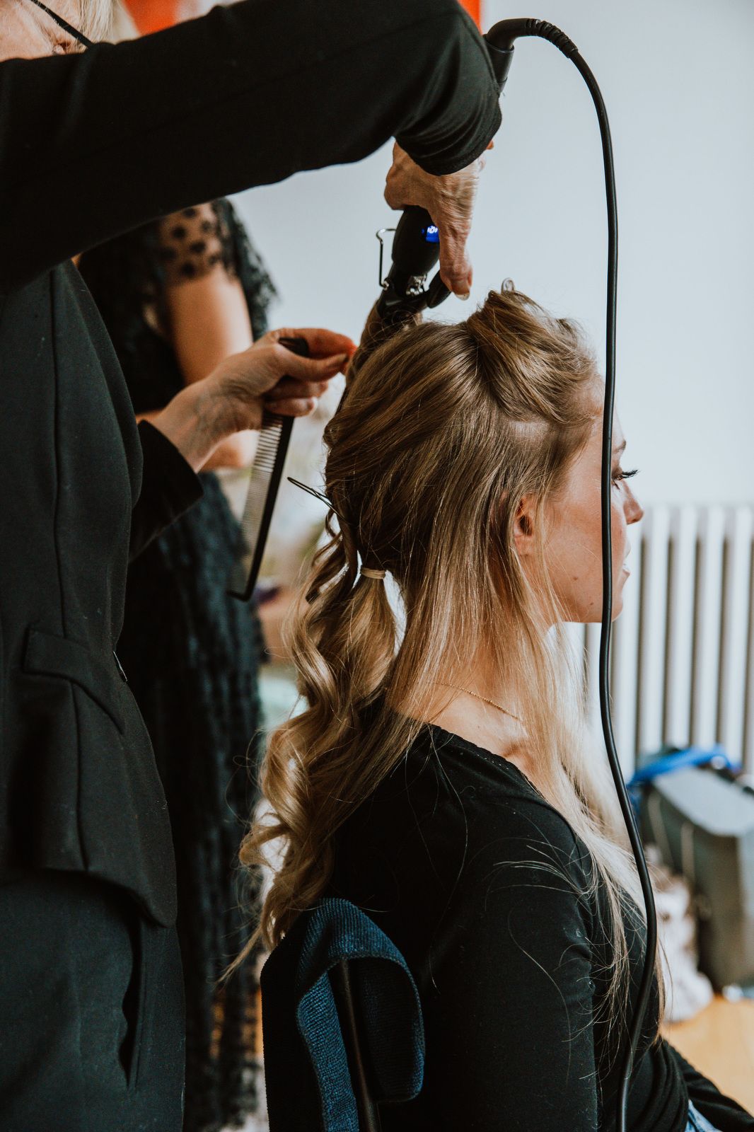 Professional hairstylist using tools and products to style client's hair in a salon setting.