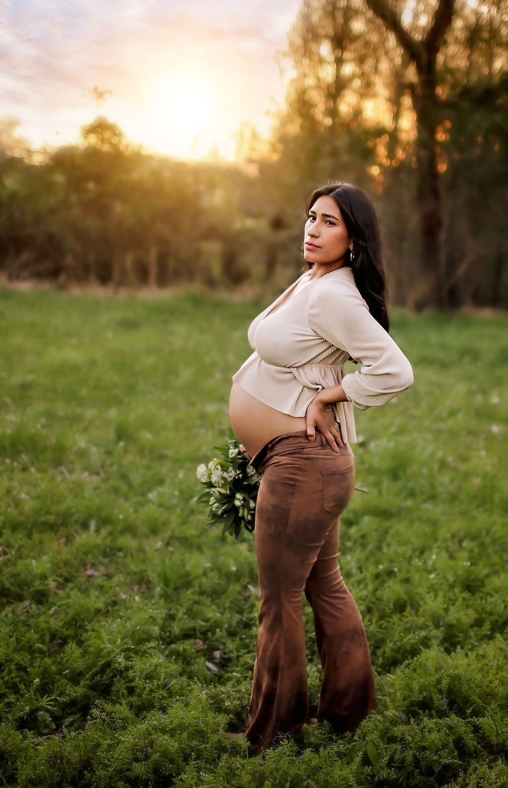 Mama in field with flowers posing for maternity session