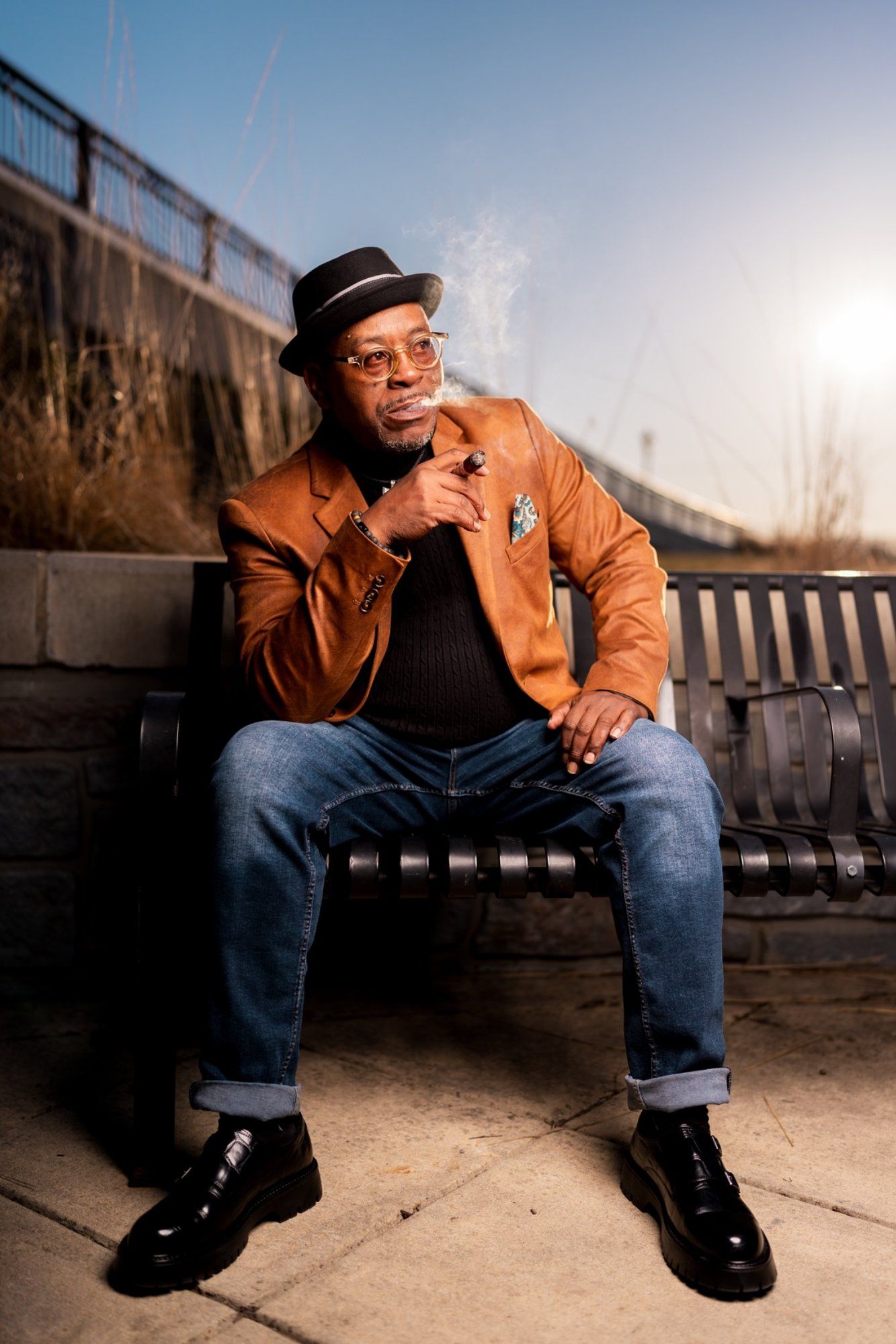 Randy Daye from CigarNewbieU sitting on a bench at the Wilmington Riverfront demonstrating how to smoke a cigar properly.