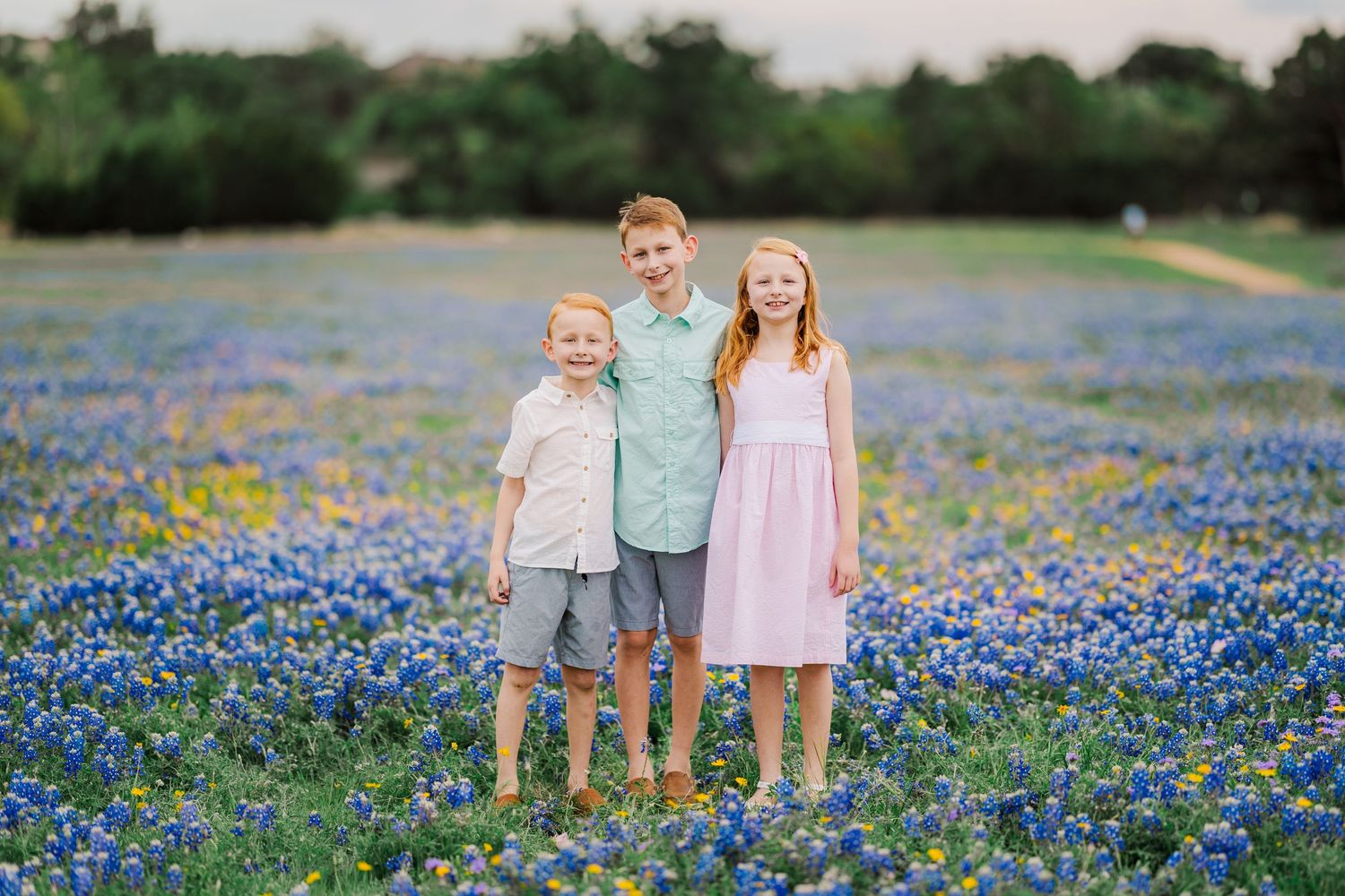 Family posing together in bluebonnet field for a spring mini session in Central Texas with vibrant wildflower backdrop.