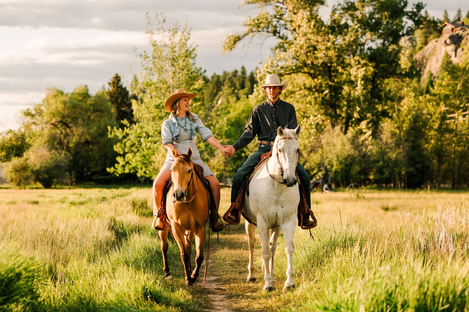 Cowboy couple riding their horses through the field holding hands captured by Equine Photographer Lauren Ann Wagner