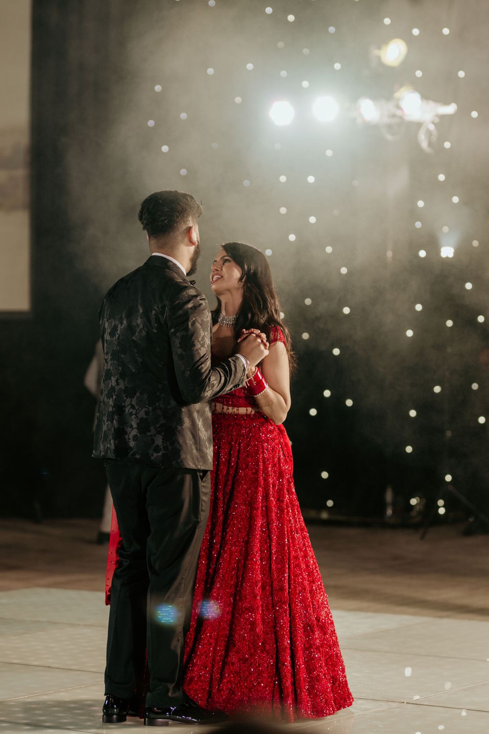 Romantic couple dancing together under sparkling lights at an indoor venue.