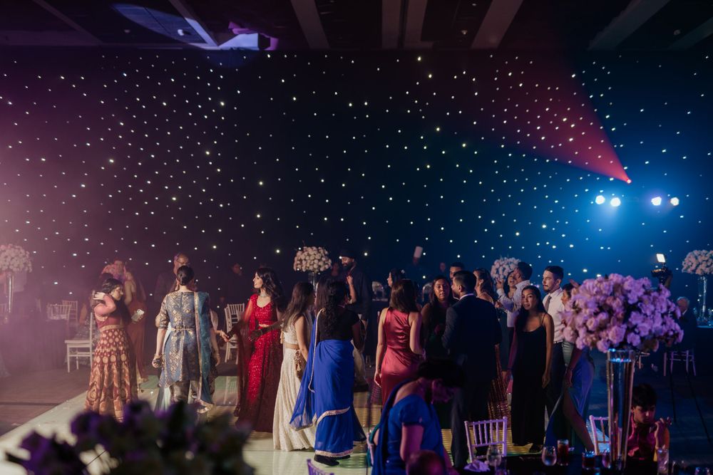 Wedding party lines up on stage during evening reception with starry lighting effects in the background.