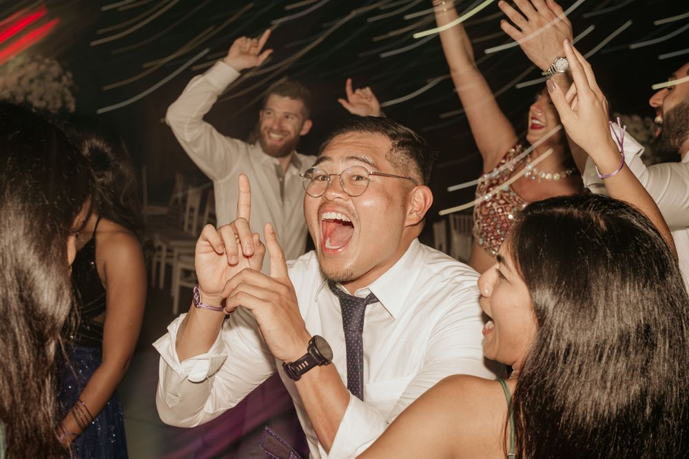 People dancing and celebrating at a lively party with dynamic lighting effects.