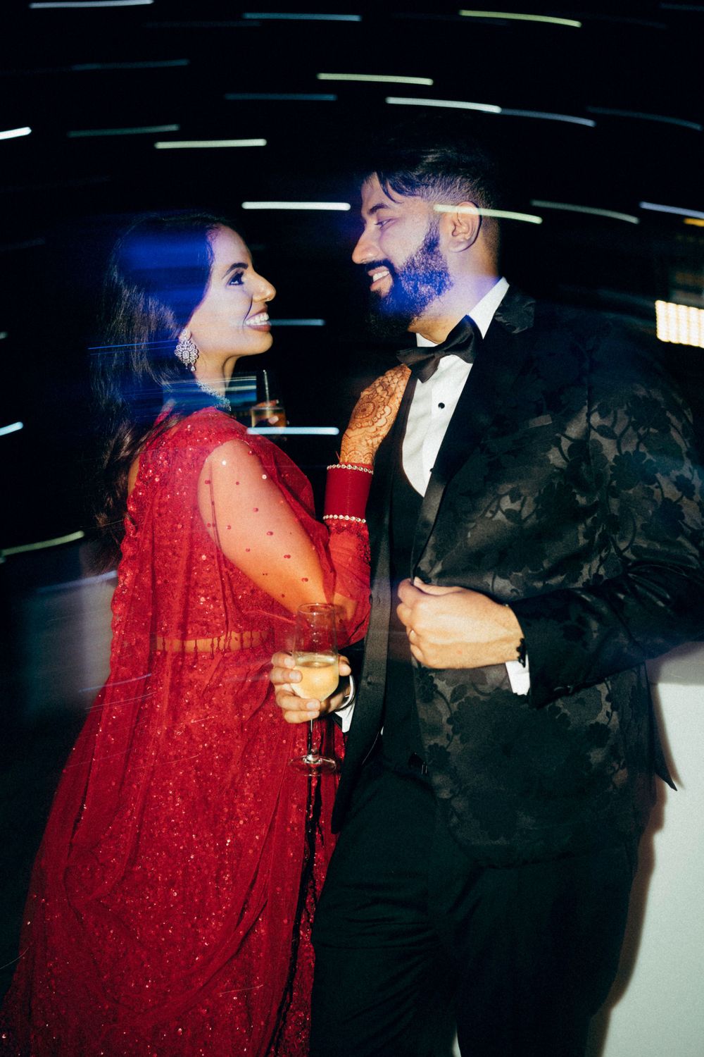 A couple in formal attire sharing a romantic moment at an evening event with a sparkly light backdrop.