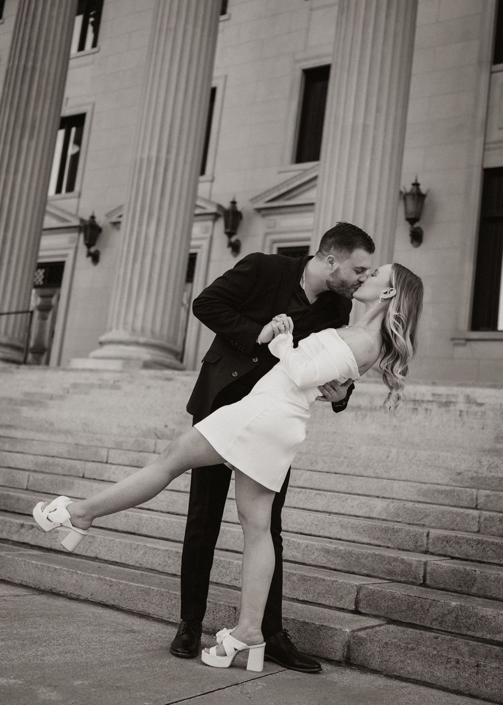 Romantic dip pose on grand stone steps in black and white photography.