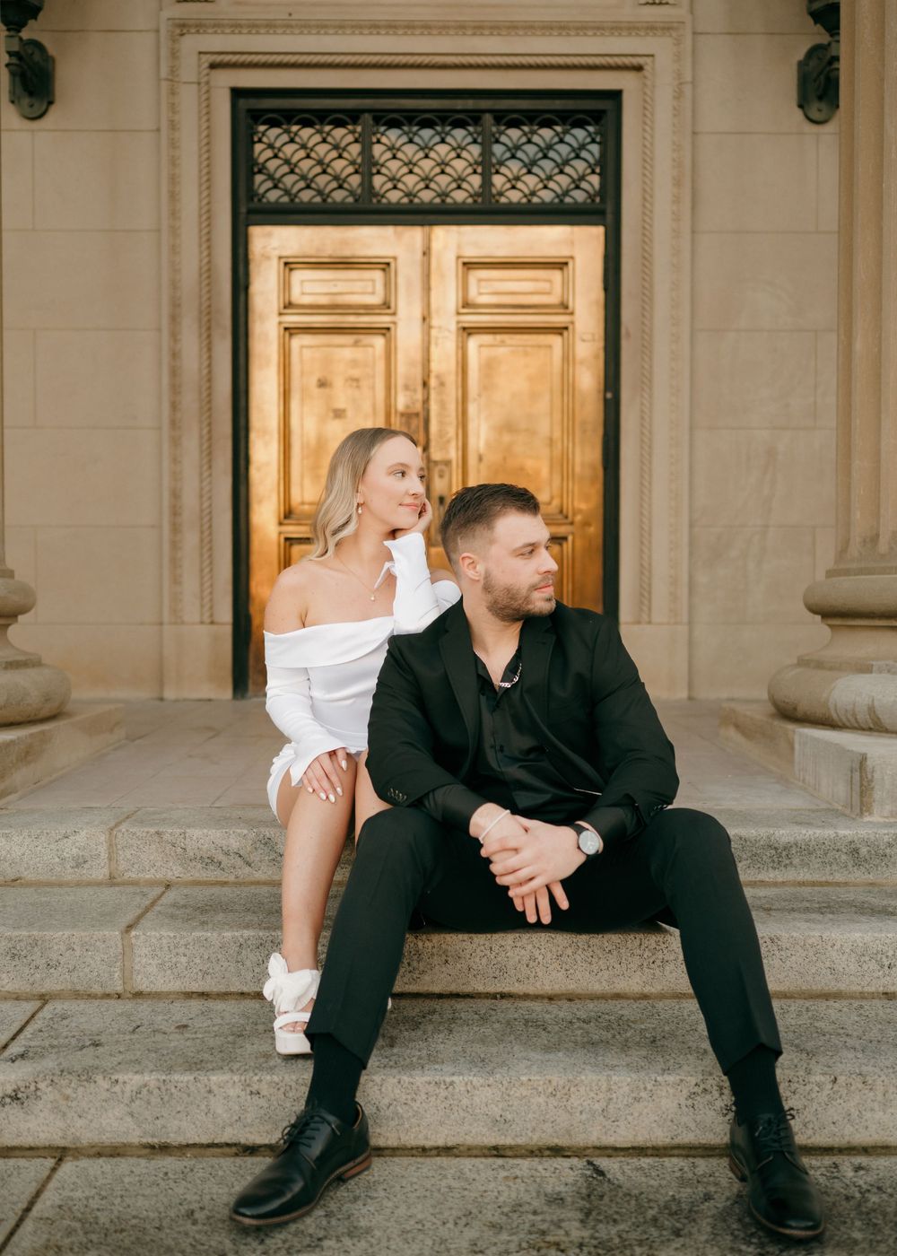 A couple sits together on stone steps in front of an ornate door in Uptown Charlotte, North Carolina.