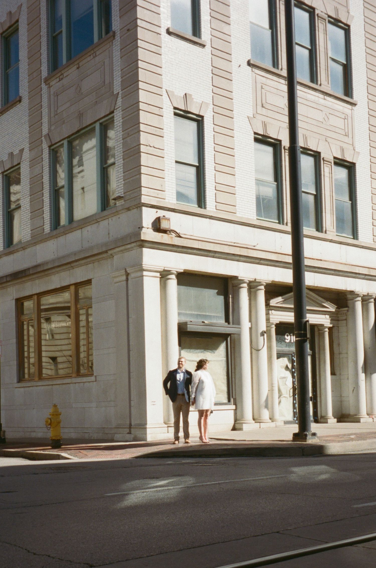 Couple standing in front of a classic stone building with large windows and columns.