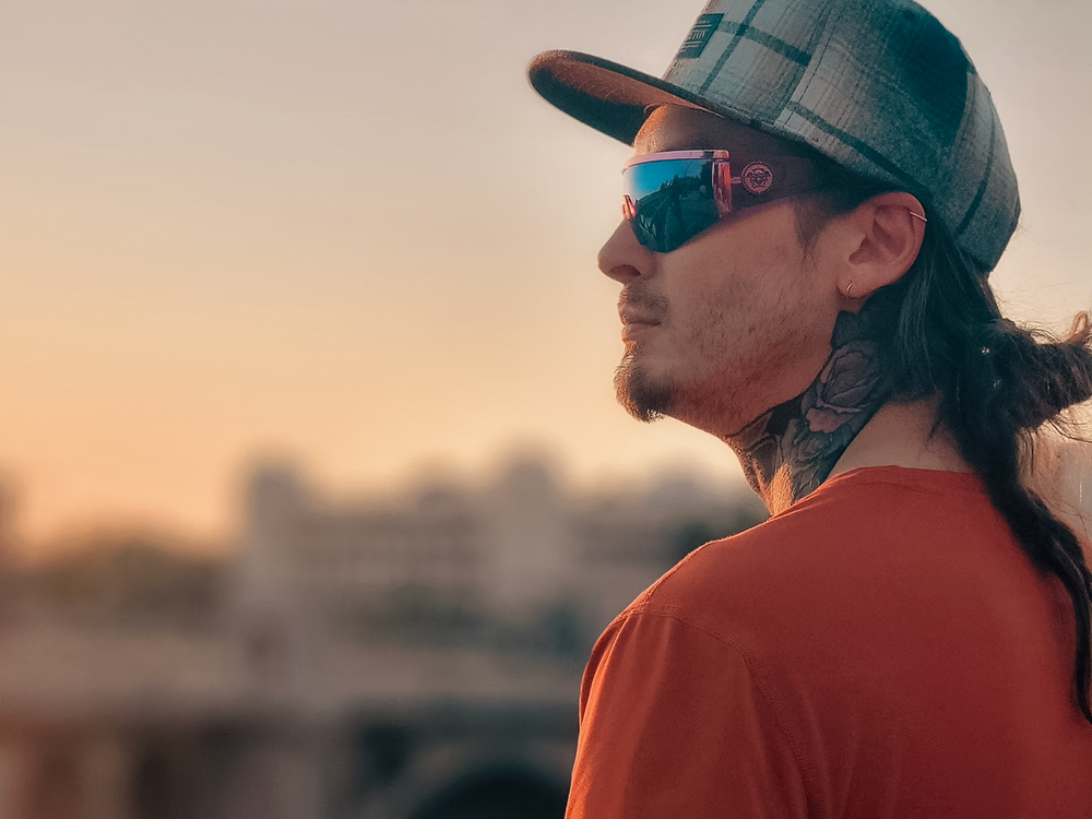Profile view of someone in a baseball cap and red shirt silhouetted against a warm sunset sky.