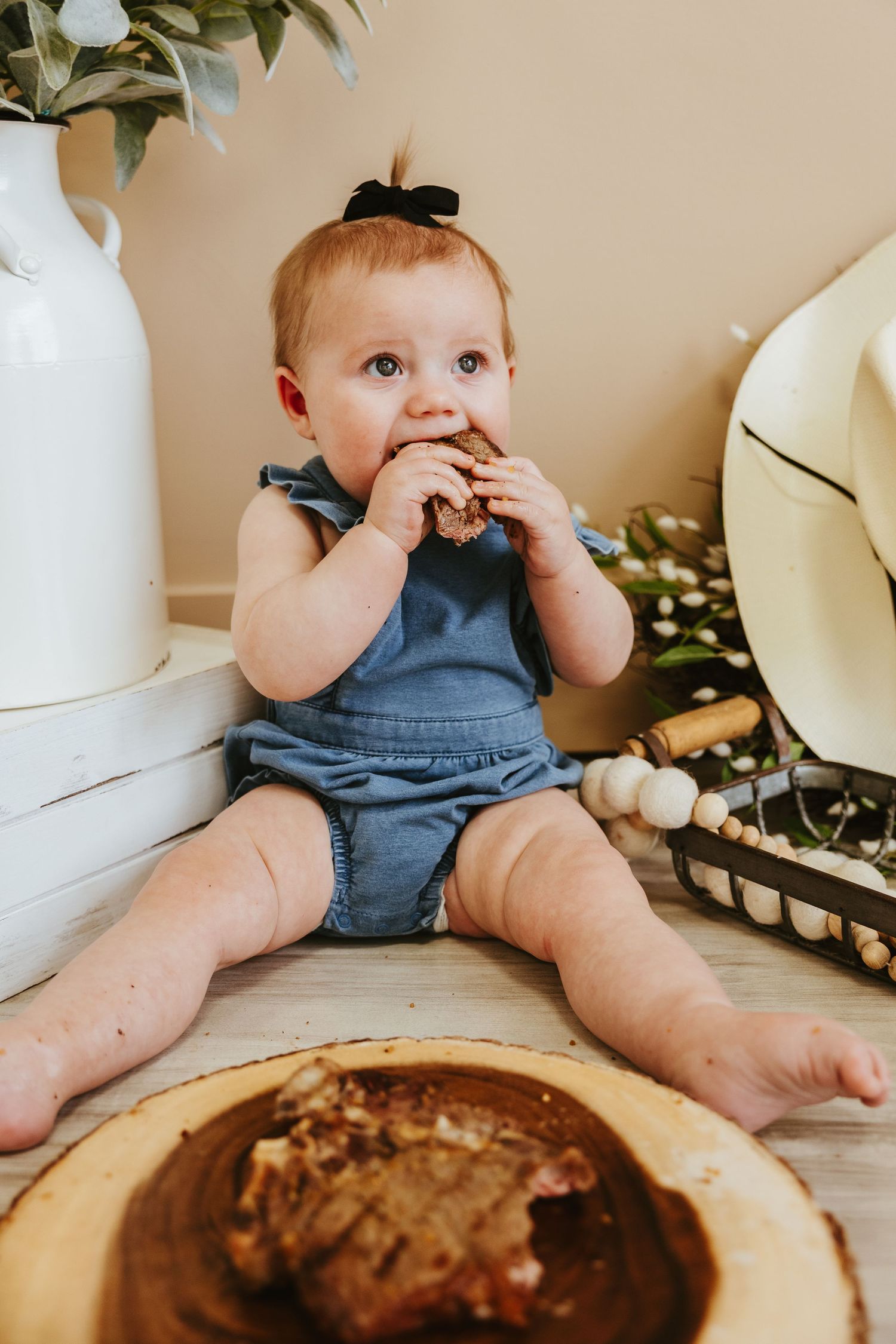 Baby in denim outfit taking bite of grilled sandwich.