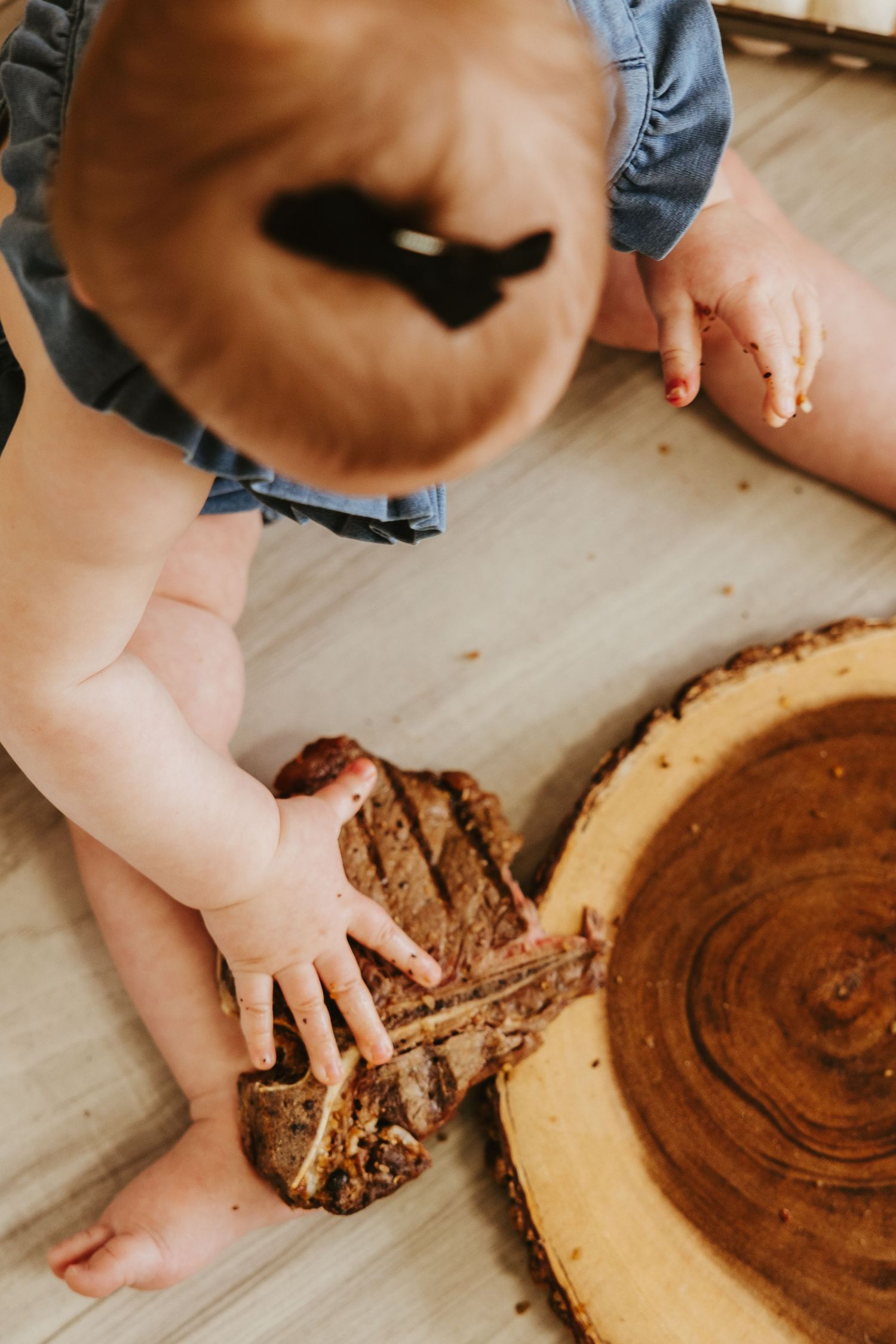Small hands reach for items on a rustic wooden slice board.
