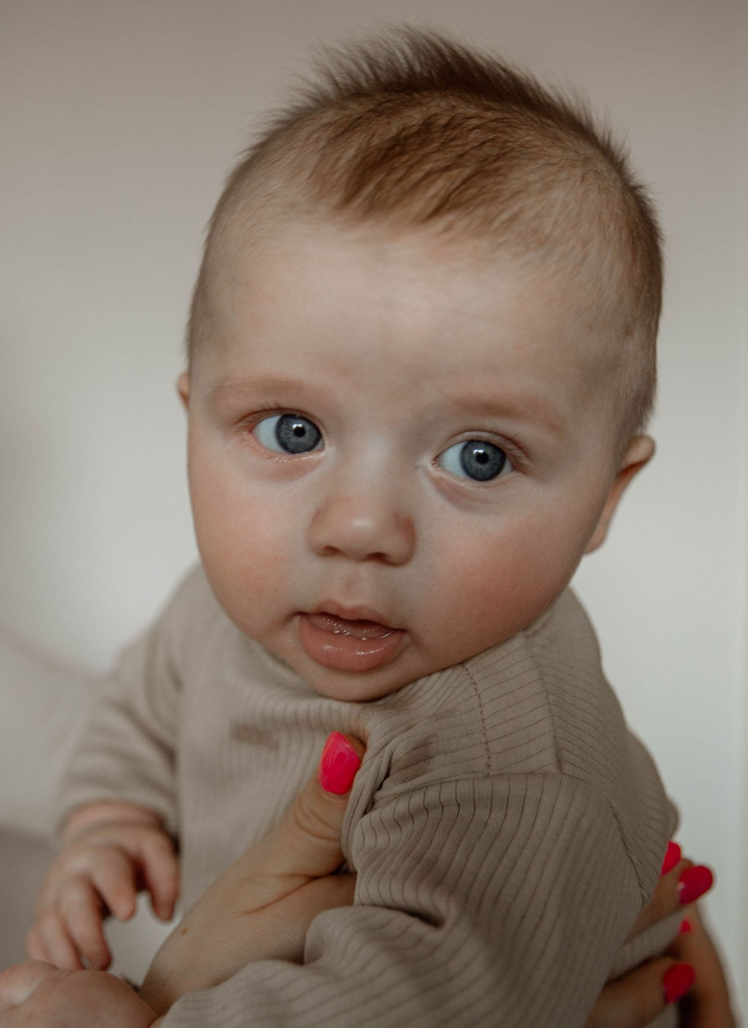 Baby in beige ribbed outfit looking directly at camera.