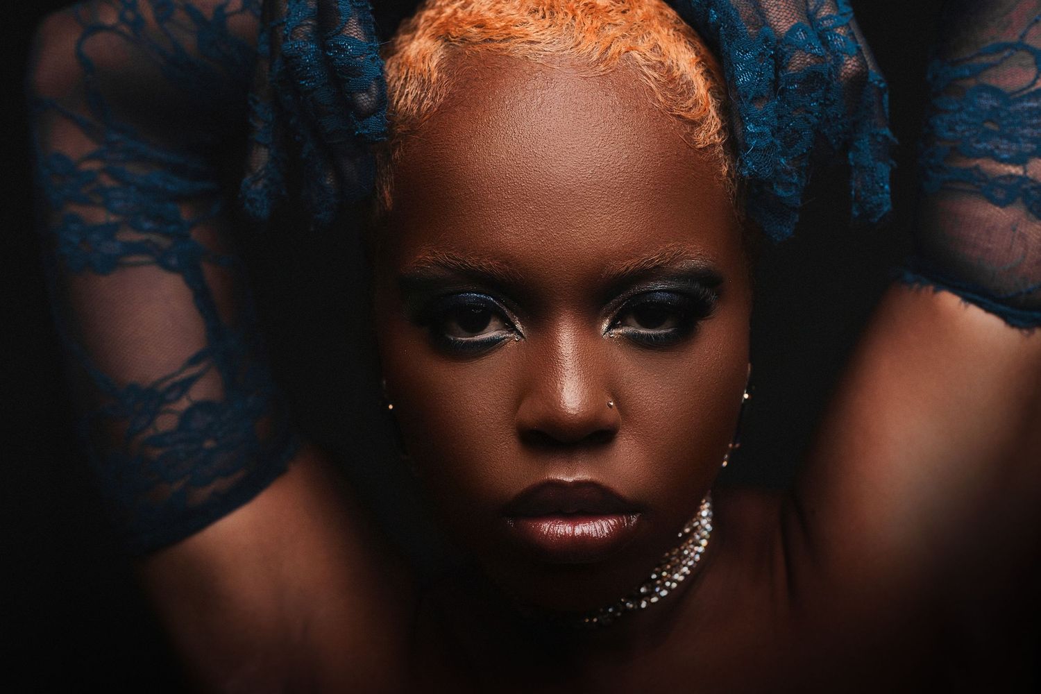 Dramatic beauty portrait with blue lace background and glamorous makeup.