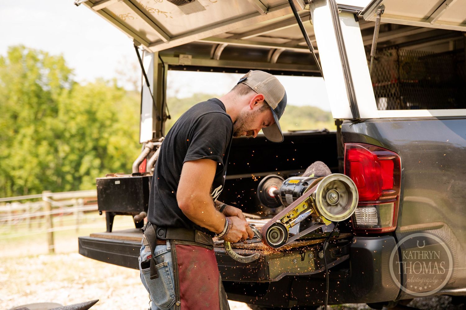 Mobile farrier preparing horseshoes in the back of a pickup truck.