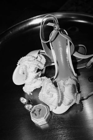 Elegant bridal shoes and accessories arranged in black and white photography.