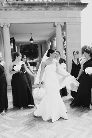 Wedding party relaxing and socializing on an elegant brick patio with white columns.