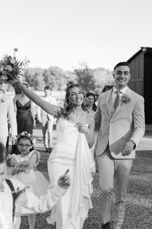 A joyful wedding celebration moment with the couple walking outdoors in black and white photography.