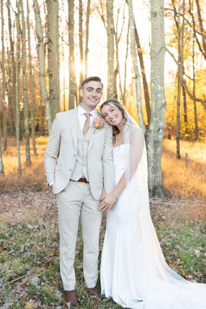 Romantic sunset wedding portrait among birch trees with golden light filtering through.
