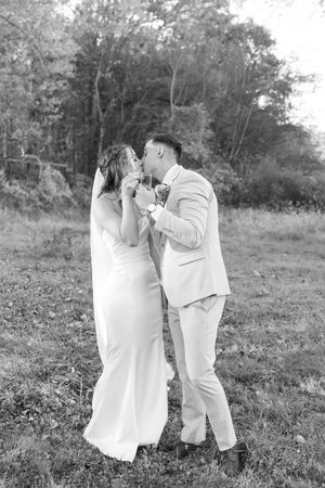 A black and white wedding photo of a couple sharing an intimate moment in a field.