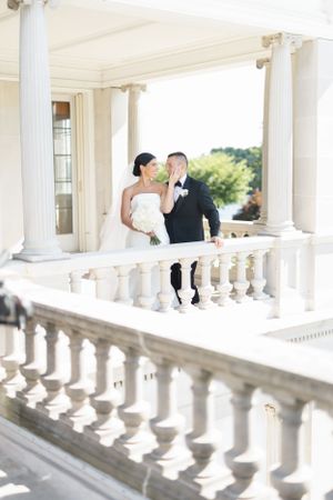 Elegant wedding photos on a white columned balcony with classical architecture.