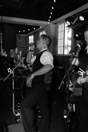 A black and white photo of a musician performing at a wedding reception.