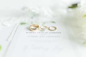 Three wedding rings arranged on white paper with elegant text visible beneath.