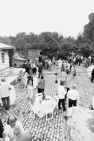 A vintage black and white photograph shows a crowd of people gathered on a cobblestone plaza during an outdoor event.