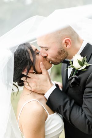 Romantic wedding portrait with white veil flowing in soft natural light.