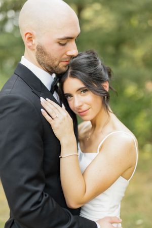 A romantic wedding portrait showing a tender embrace against a soft natural background.