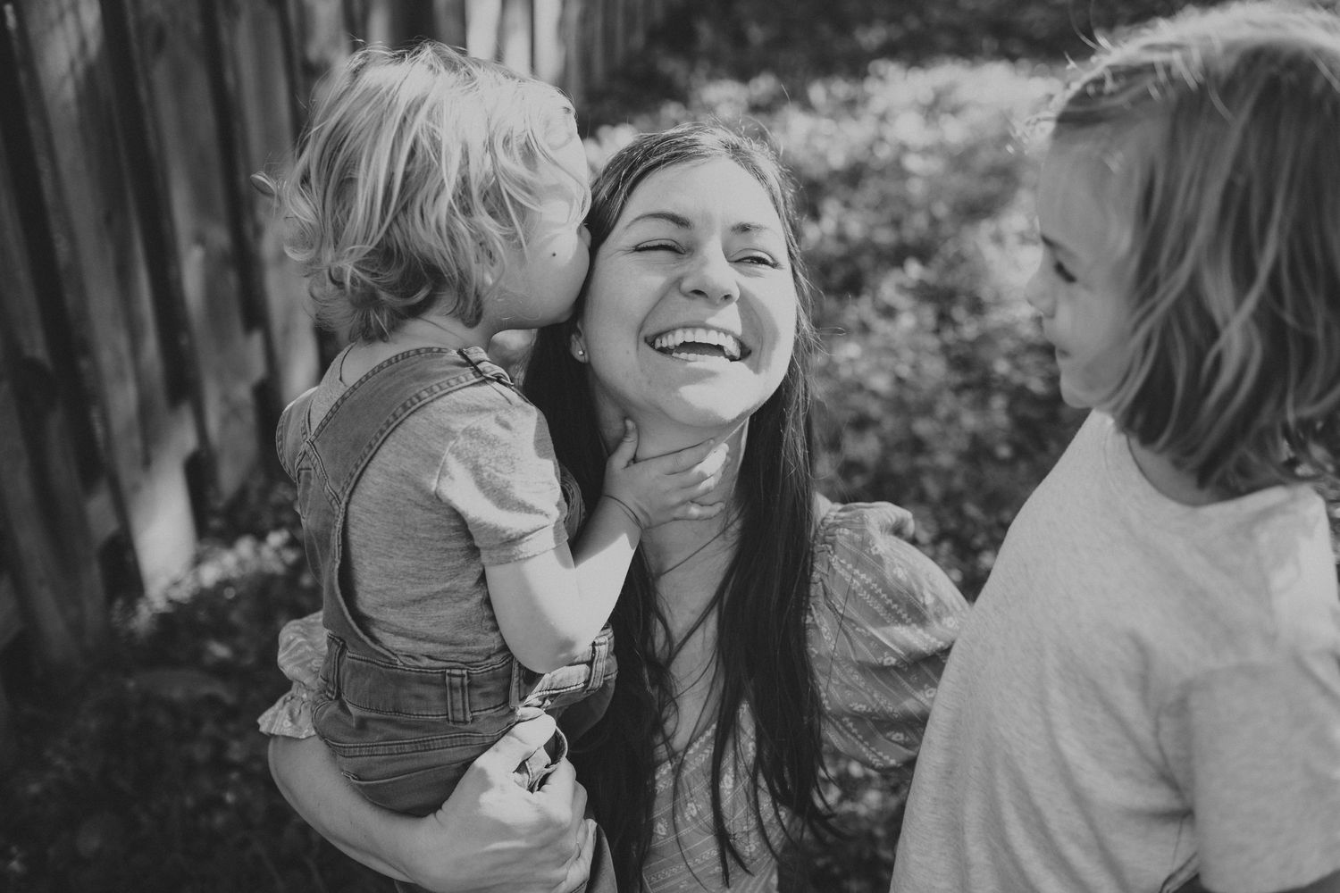 A touching black and white family moment captured in natural outdoor lighting.