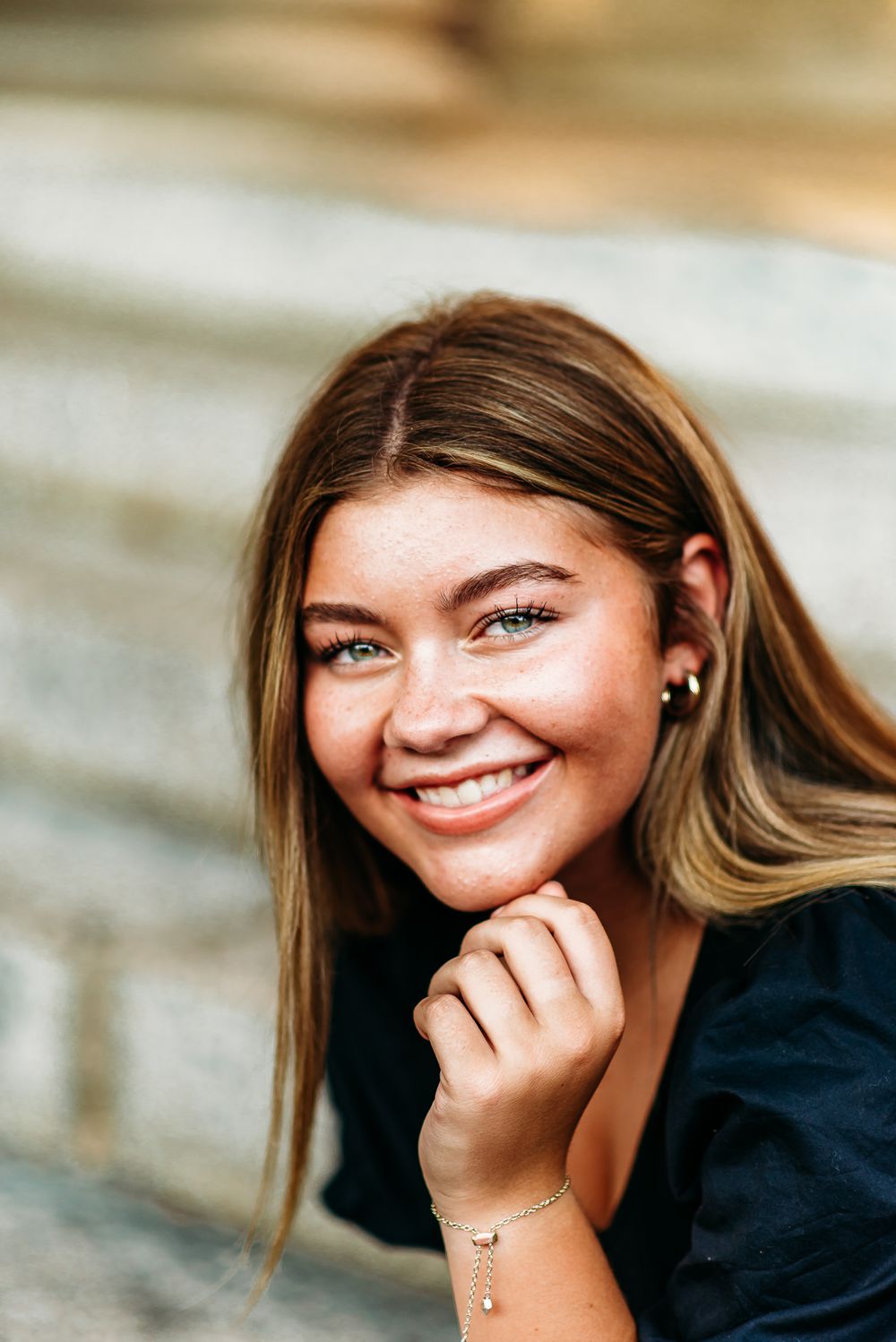 Portrait featuring soft lighting and natural smile against textured stone background.