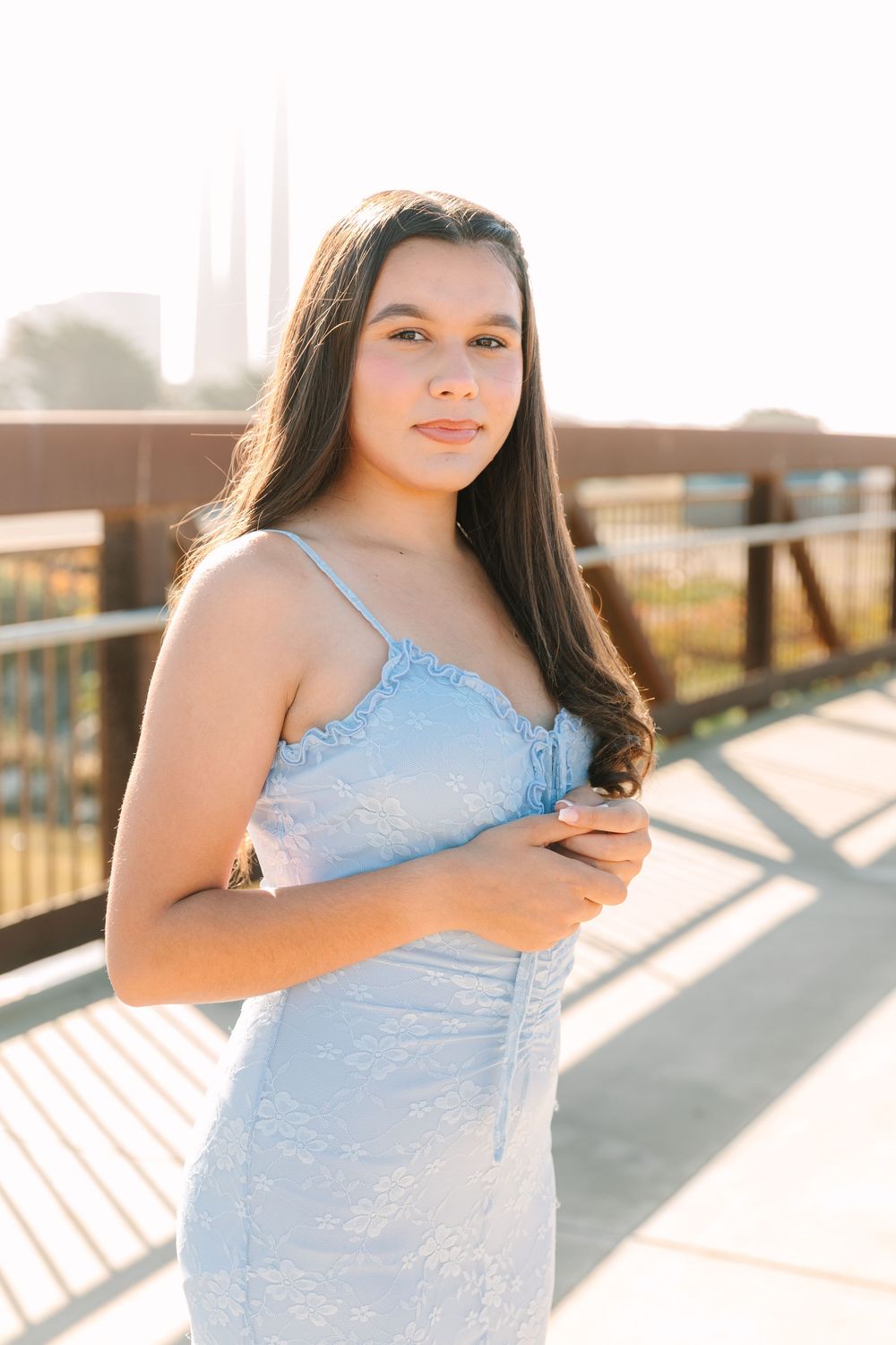 A series of outdoor portrait photos in soft sunlight showing someone wearing a light blue dress against a wooden railing.