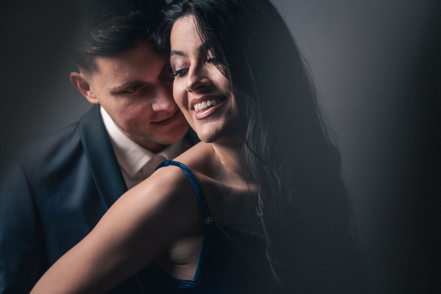 Intimate couple portrait with dramatic lighting and shadows creating romantic mood.