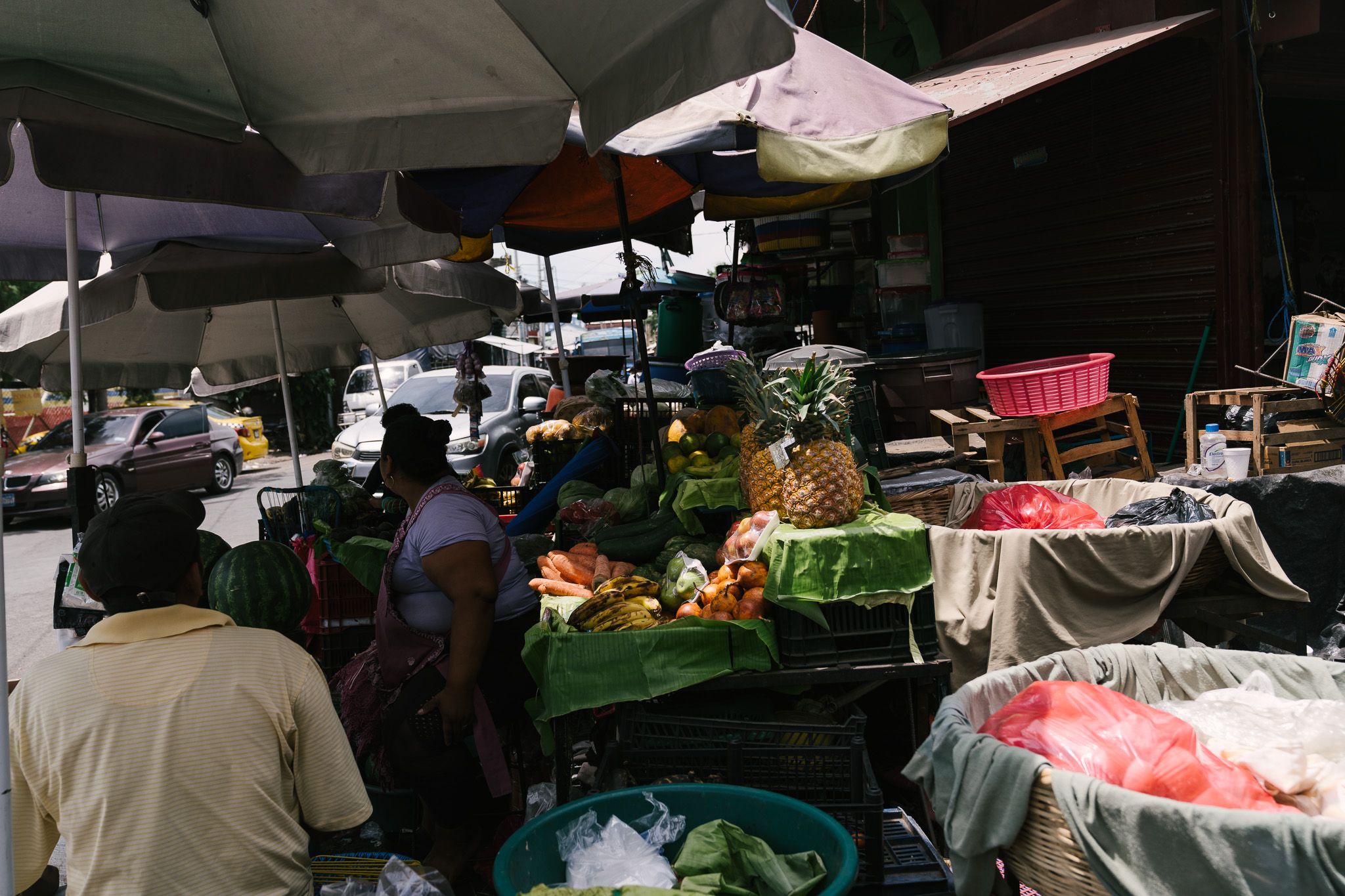 Covered market stalls selling fresh produce under green umbrellas.
