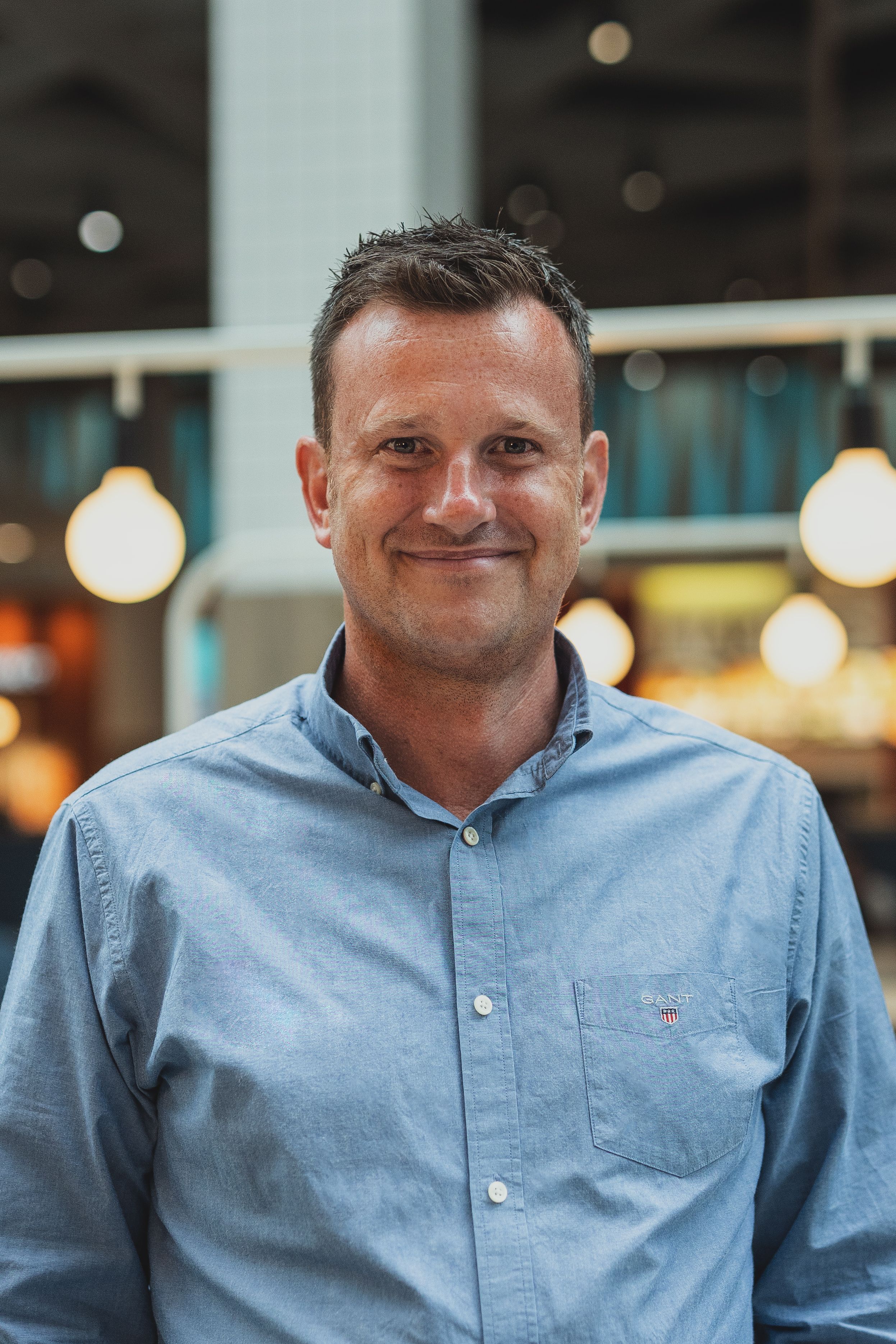 Casual portrait in light blue button-down shirt with indoor lighting.