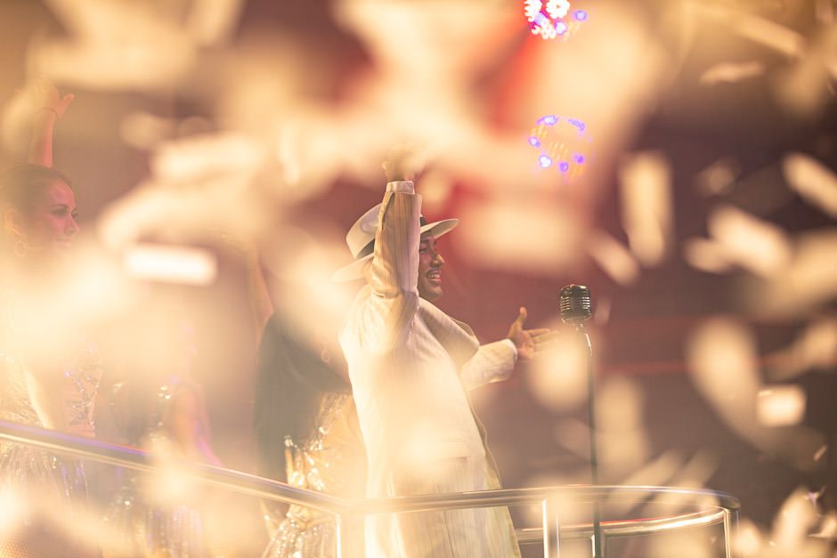 A silhouetted figure performs on stage with dreamy bokeh lights and sparkles creating a magical atmosphere.
