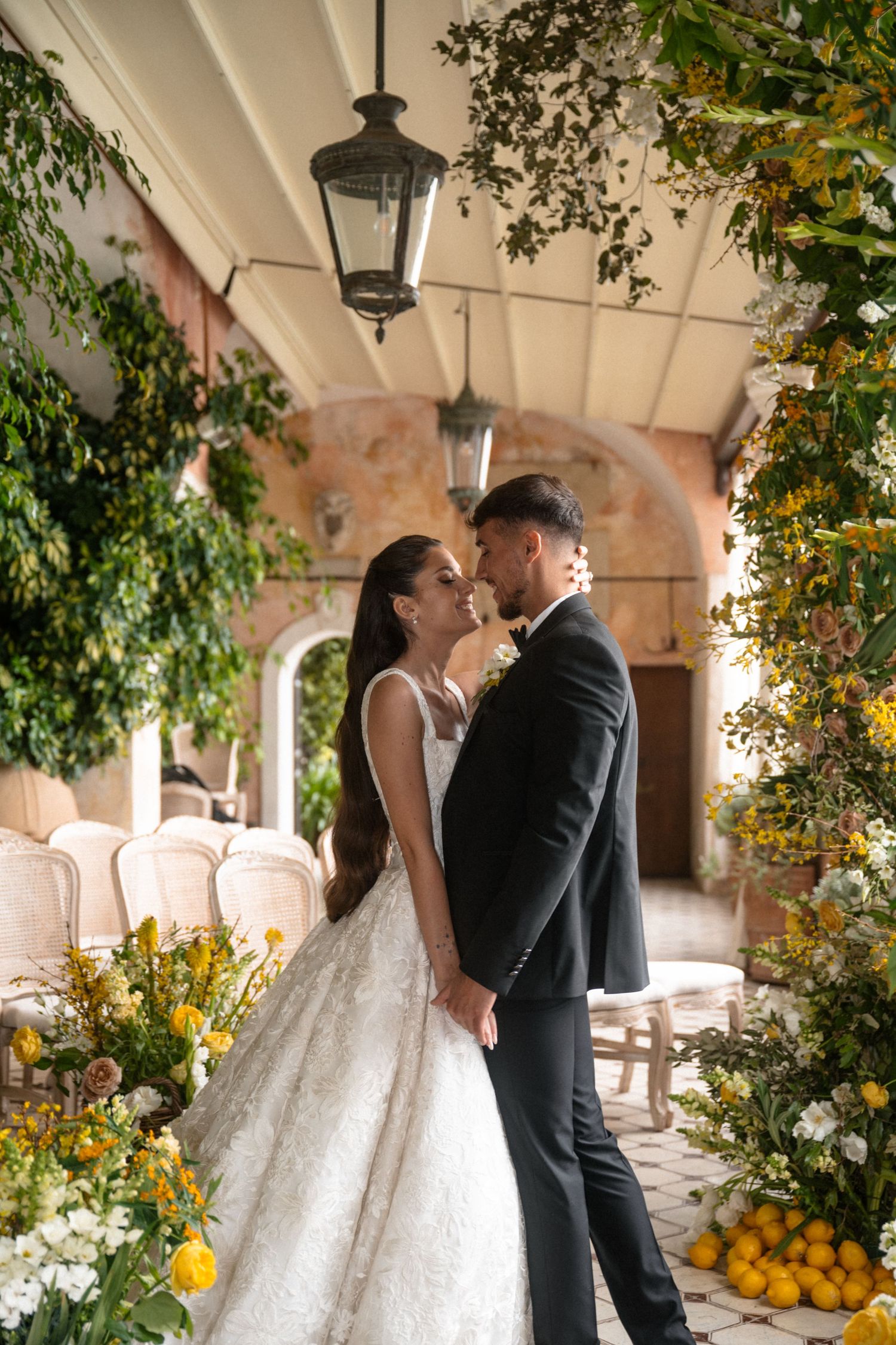 Wedding ceremony setting under stone archway decorated with yellow flowers and citrus accents.