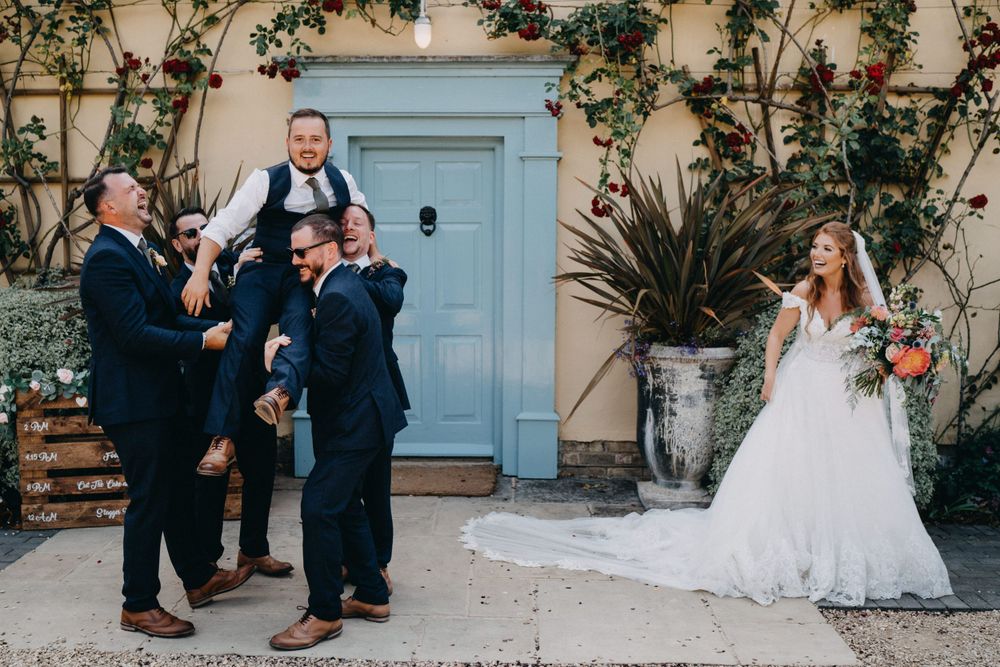 Playful wedding party moment outside a blue door with climbing vines.