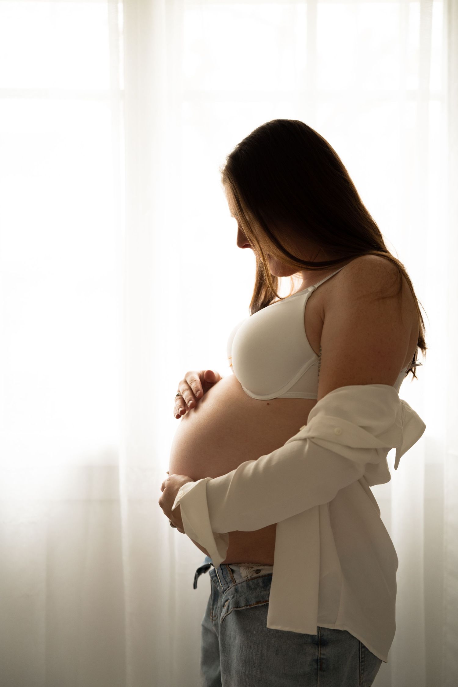 photo d'une femme enceinte en contre jour en train de regarder son ventre