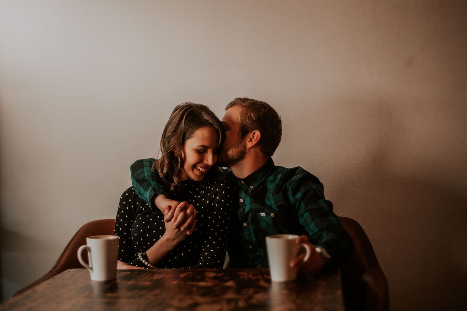 A cozy coffee date moment shared between a couple at a wooden table.