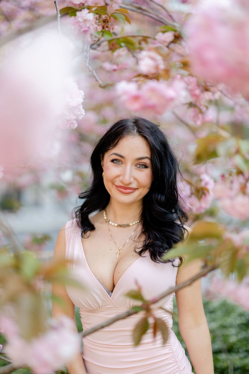 Spring portrait among pink cherry blossoms wearing pink formal dress.