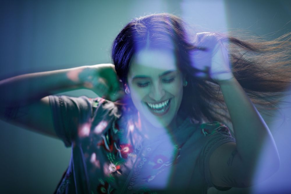 Dynamic shot of person with flowing hair dancing in ethereal blue and green lighting.