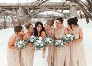 Bride with bridesmaids in champagne dresses holding white bouquets in snow. Wedding photography.