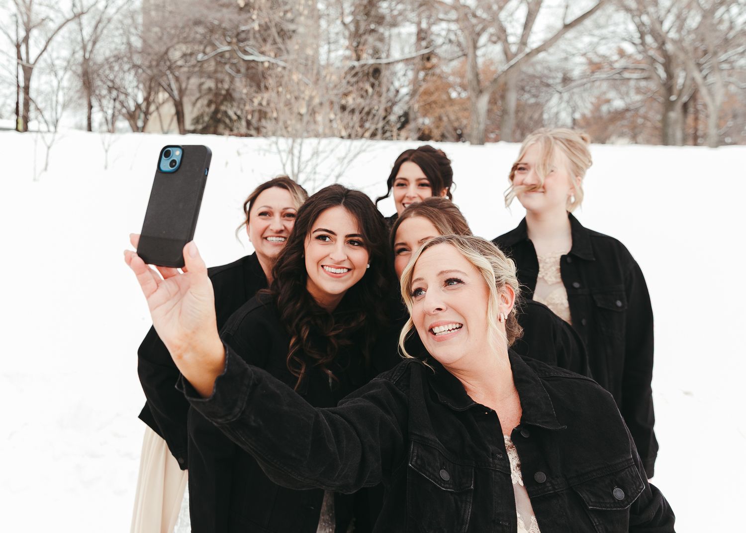 Group of women taking a selfie together outdoors in winter snow. Wedding photography.