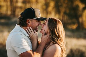 Couple shares a tender almost-kiss moment outdoors in warm golden sunlight during engagement session. Engagement photos.