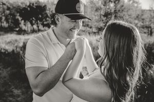 Black and white photo of laughing couple sharing a playful moment during outdoor engagement session. Engagement photos.
