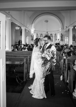 Black and white photo of bride and groom sharing a moment in a historic church aisle.
