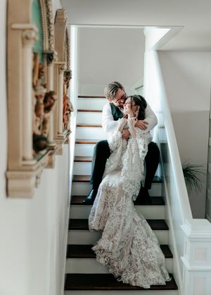 Bride and groom share a romantic kiss on a staircase in an elegant venue.
