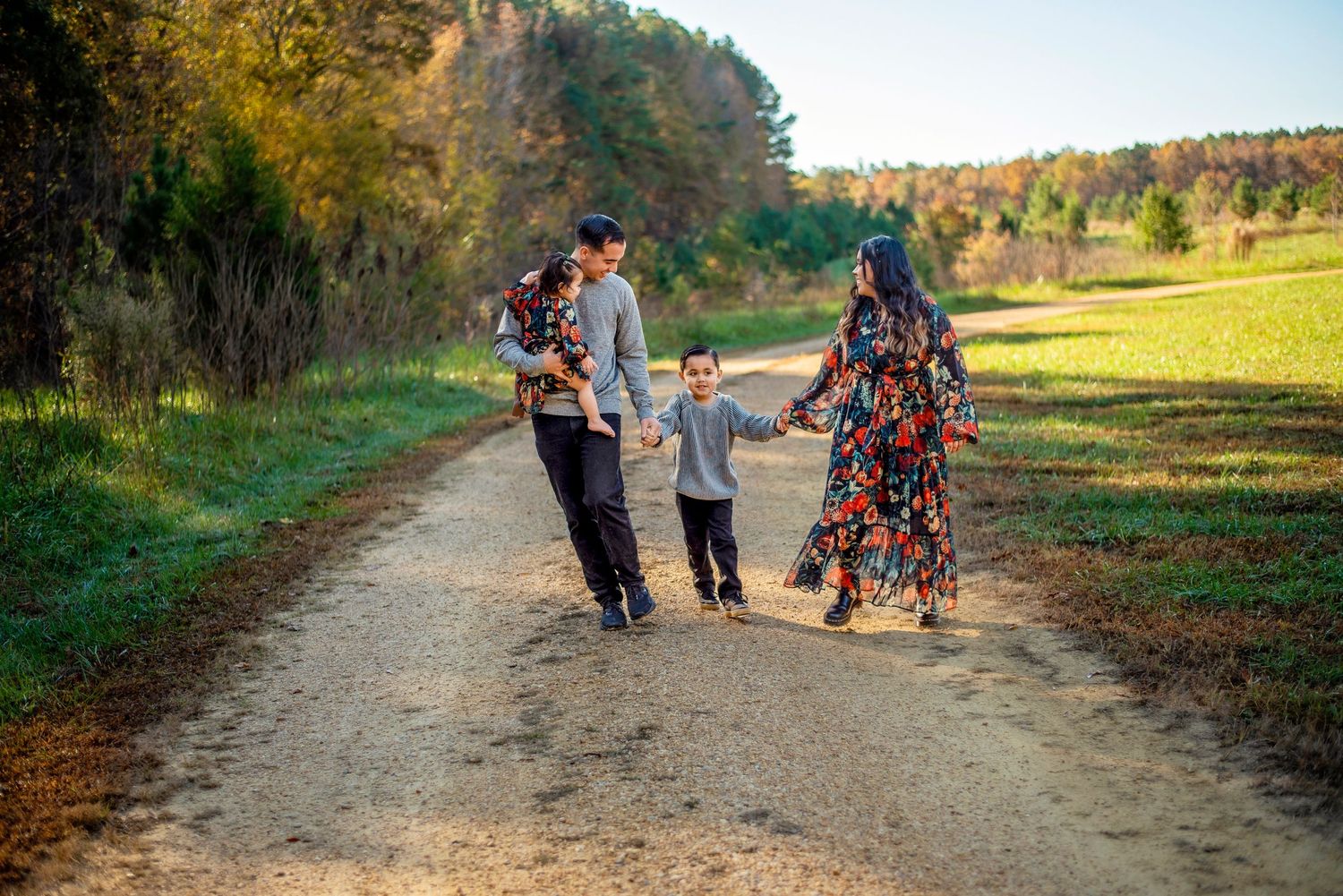 Family walking together on a dirt path during golden hour in autumn.